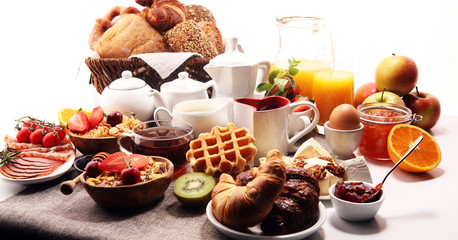 Huge healthy breakfast on table with coffee, orange juice, fruits, waffles and croissants. Good morning concept.