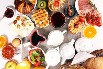 Huge healthy breakfast on table with coffee, orange juice, fruits, waffles and croissants. Good morning concept.