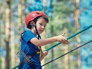 European boy on the rope way in the forest.