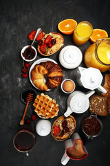 Huge healthy breakfast on table with coffee, orange juice, fruits, waffles and croissants. Good morning concept.