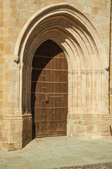 Big wooden door with medieval stone arches at Caceres
