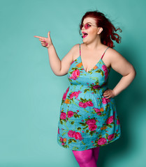 Overweight redhead lady plus-size woman in sunglasses shows a gesture sign finger - gun, aimed at...