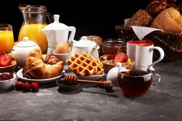 Huge healthy breakfast on table with coffee, orange juice, fruits, waffles and croissants. Good morning concept.