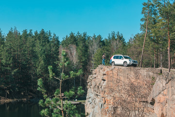 young man at edge with beautiful view of lake near white suv car