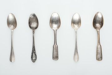 top view of shiny aged silver empty spoons in row on white background