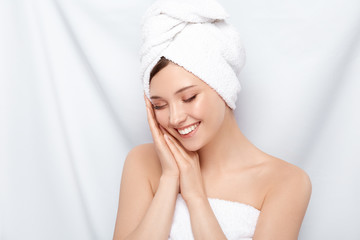 pretty girl in bath towel compose her arms near face and laughs with her eyes closed, happy woman...