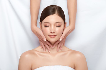 Naklejka premium pretty girl having massage for her neck lying on white, body treatment and spa theraphy for female, beautician working on woman's body