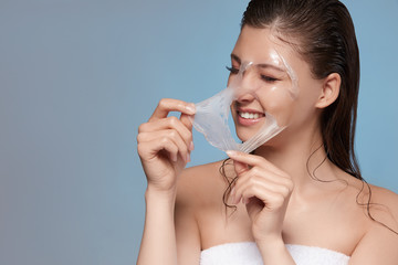 lady in bath towel and with wet hair removing peeling mask with her eyes closed, copy space, young girl doing facial treatment