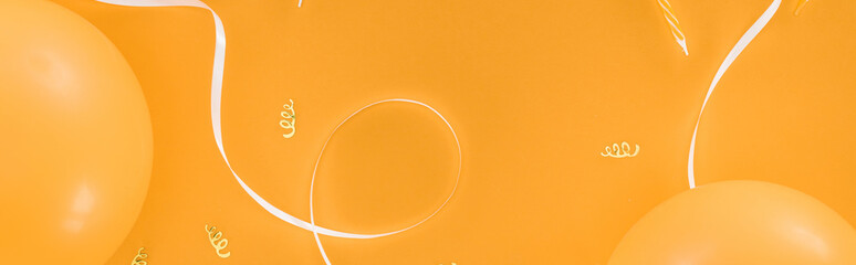 Panoramic shot of yellow balloons and party decoration on orange background