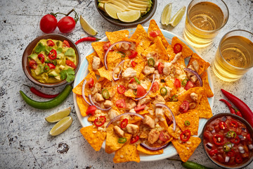 A plate of delicious tortilla nachos with melted cheese sauce, grilled chicken