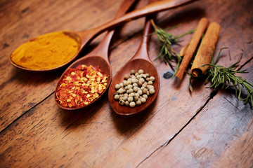 Close-up of handful dry herbal spices on wooden spoons for cooking on wooden table