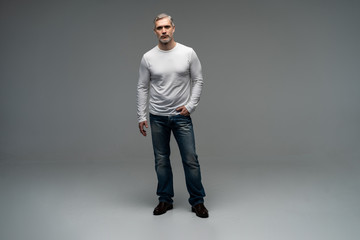 Full body portrait of relaxed mature man standing over gray background.
