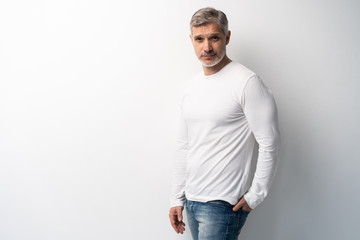 Cheerful man of middle age against white background, wearing jeans and white T-shirt, mid shot.