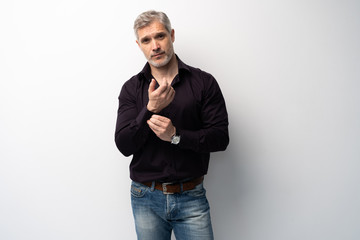 Cheerful man of middle age against white background, wearing jeans and black shirt, mid shot.