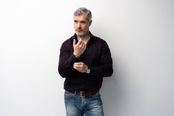 Cheerful man of middle age against white background, wearing jeans and black shirt, mid shot.