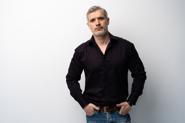 Cheerful man of middle age against white background, wearing jeans and black shirt, mid shot.