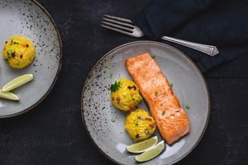 Grilled Salmon Fillets with Saffron Risotto and Lime on Dark Background