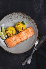 Grilled Salmon Fillets with Saffron Risotto and Lime on Dark Background