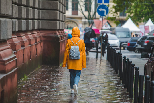 Woman In Yellow Raincoat Walking By City Streets Under Rain