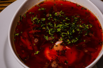 Beats soup, borsch with sour cream; bead and pickles on a background. borsch in a white dish, slices of bread on a wooden cutting board, whole pickles in a wooden dish.