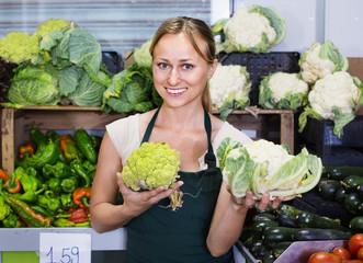 Portrait of woman working in fruit shop showing fresh cabbage