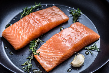 Fresh and Raw Salmon Steaks in Frying Pan with Thyme and Garlic