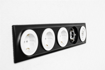 five black white sockets in the white wall