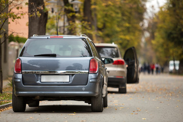 Gray shiny car parked in quiet area on asphalt road on blurred bokeh background on bright sunny day. Transportation and parking concept.