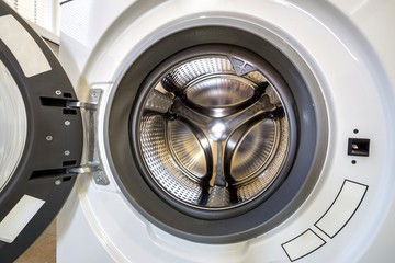 Close-up detail of modern washing machine interior with open door interior. Silver shiny stainless...