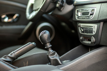 Luxurious car black leather interior. Close-up detail of handbrake manual brake and gearshift stick on blurred dashboard background. Transportation, design, modern technology concept.