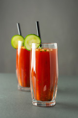Glasses of tasty tomato juice isolated on gray table