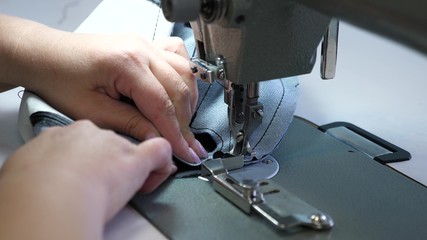 process of sewing leather goods. needle of the sewing machine in motion. two needles of the sewing machine quickly moves up and down, close-up. Tailor sews black leather in a sewing workshop.