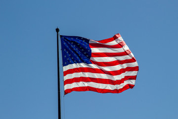 Obraz premium USA American flag waving in the wind on clear blue sky in background