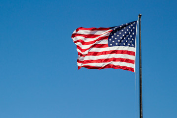 USA American flag waving in the wind on clear blue sky in background