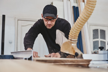 Carpentry Creations. Sawing up of a wooden board on a sliding table saw. Woodworking and carpentry...