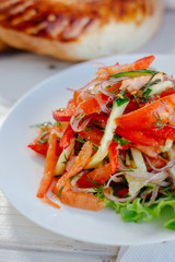 Vegetable salad on the white plate. Achik Chukchuk salad with tomatoes and onion.