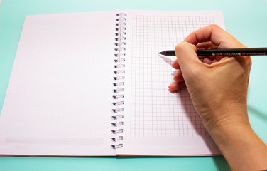 Back to school, education concept for educantion and new academic year. Notebook and black pencil, blue paper background. Mock-up copy space.