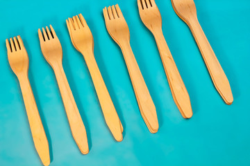 Disposable ecological wooden bamboo fork and spoon pattern on a blue background. Environment friendly flat lay with free copy space for text. Selective background