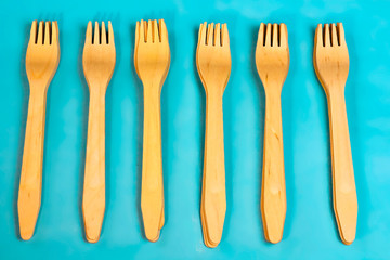Disposable ecological wooden bamboo fork and spoon pattern on a blue background. Environment friendly flat lay with free copy space for text. Selective background