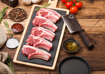 Fresh raw butchers lamb beef cutlets on chopping board with vintage meat hatchet and hammer on...