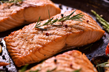 Grilled salmon fish with various vegetables on pan on the flaming grill