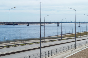 Obraz premium Panorama of big river, riverside with roadway and bridge across the river