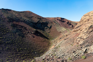Timanfaya National Park, mountains of fire at Lanzarote, Canary Islands, Spain. Unique panoramic view of spectacular corrosioned lava ground layers s of a huge volcano cone.