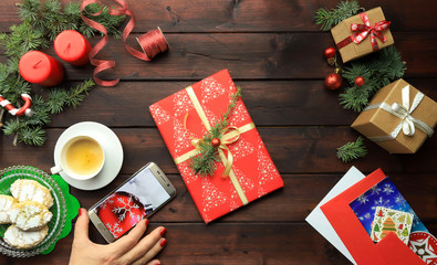 Obraz na płótnie Canvas Mani femminili che tengono regalo di Natale su un tavolo di legno con decorazioni natalizie. Vista dall'alto sul posto di lavoro di Natale.