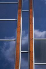 Facade with glass and tropical hardwood reflecting vibrant blue sky with clouds 