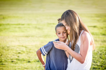 Cute young girls watching viral social media video on mobile cell phone outdoors. Teenage friends connecting with the world around them