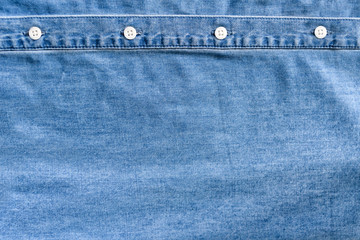 Light blue denim fabric. White button placket. Clothes concept.