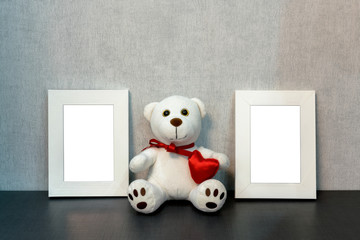 White empty frame for a photo or a picture and a teddy bear toy next to in the style of home interior, mock-up
