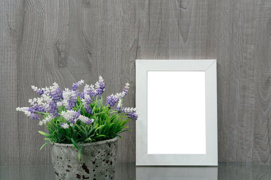 white wooden photo frame on a glass table, next to a pot with a decorative flower, design element, mock-up