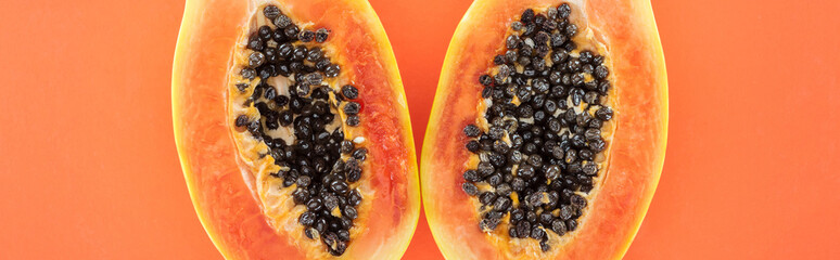 panoramic shot of ripe exotic papaya halves with black seeds isolated on orange